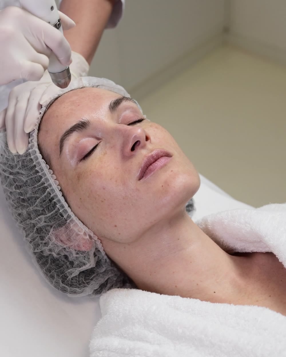 Client relaxing during a facial in a bright treatment room
